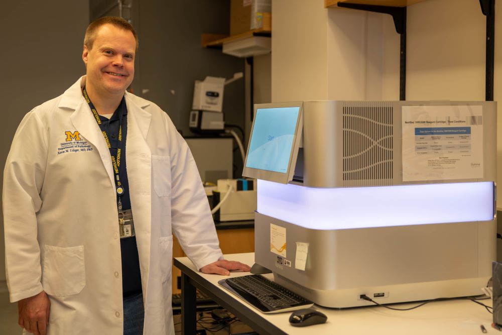 Dr. Aaron Udager with a Next Generation Sequencer in his research laboratory
